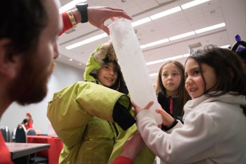 Presenter and kids looking at an ice core sample