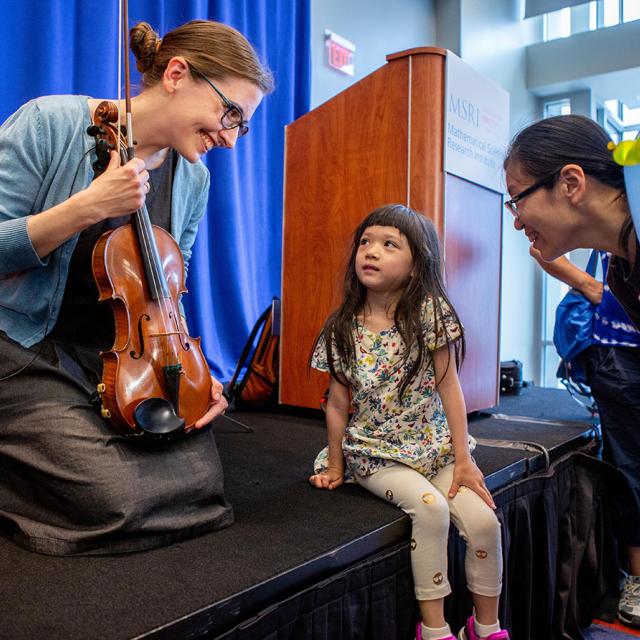 2019 festival presenter Lillian Pierce holds violin and talks to girl
