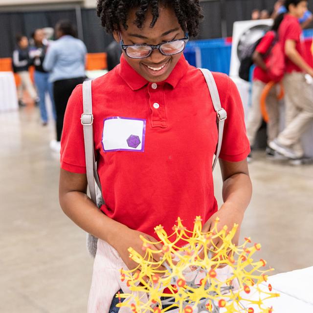 girl smiling at geometric sculpture at National Math Festival 2019